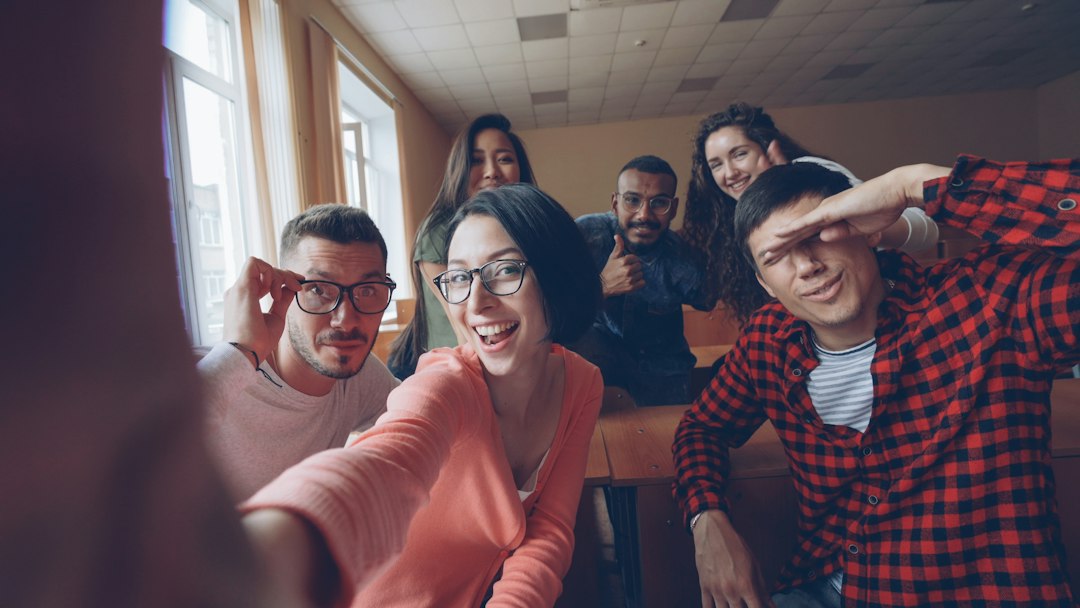 A group of students smiling together for a selfie in a lecture room
